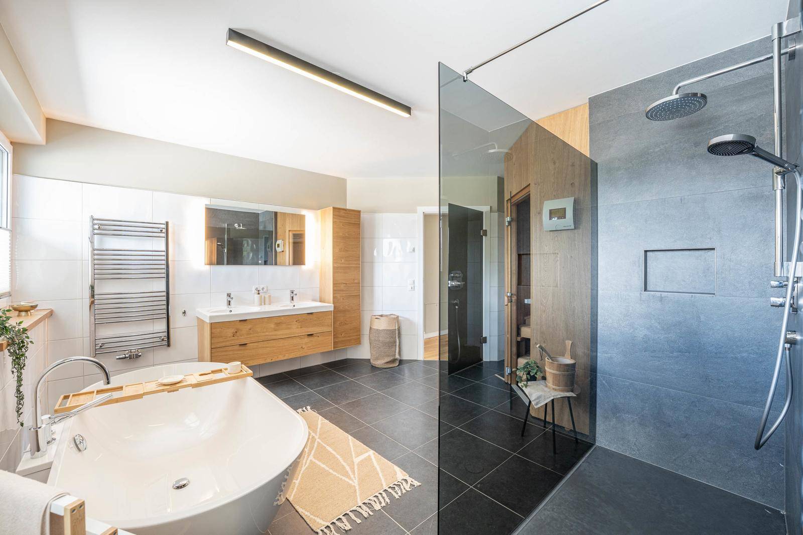 Geräumiges Badezimmer mit Sauna, freistehender Badewanne und großer Regendusche.