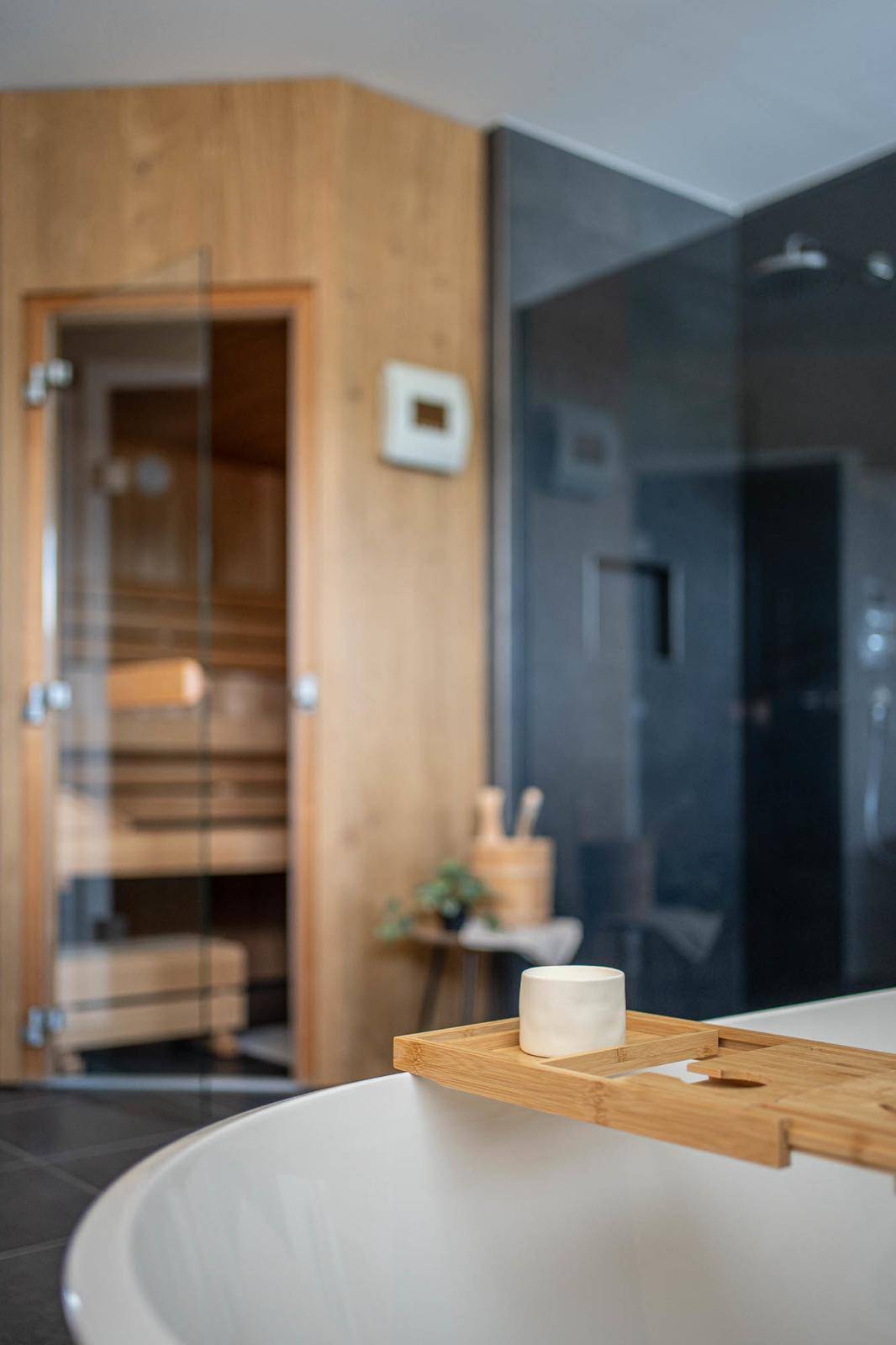 Detailaufnahme der freistehenden Badewanne mit Blick auf die Sauna.