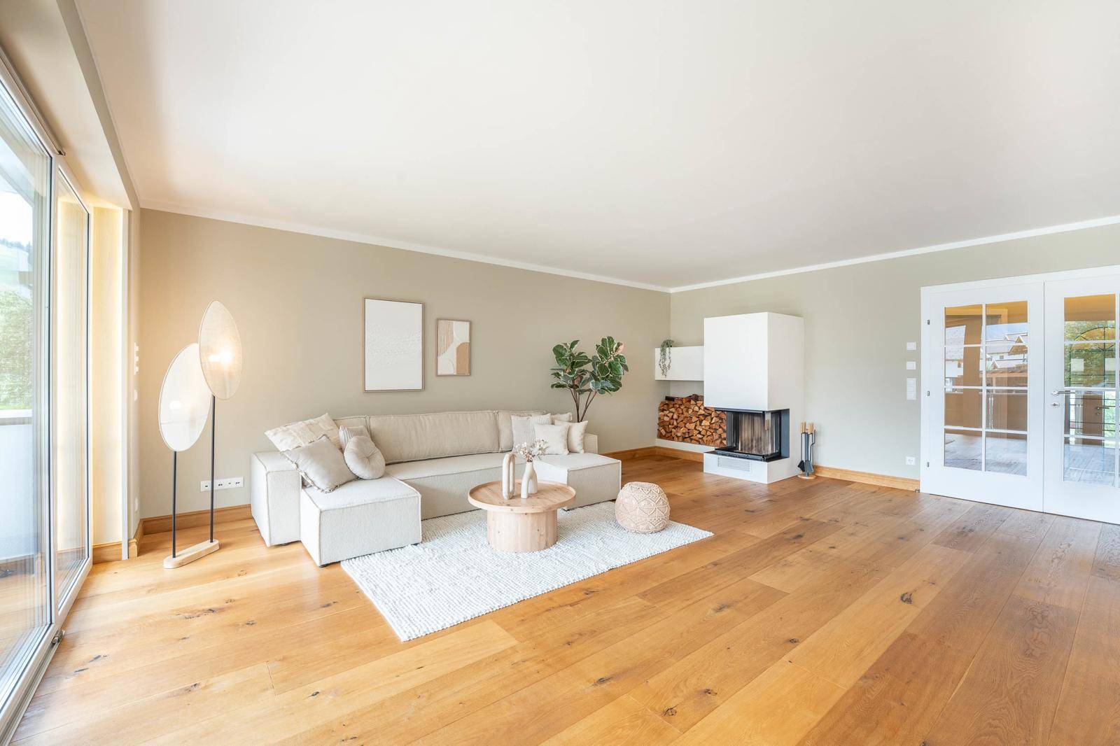 Gemütliches Wohnzimmer mit Kamin, großem Sofa und Zugang zu einem Außenbereich.
