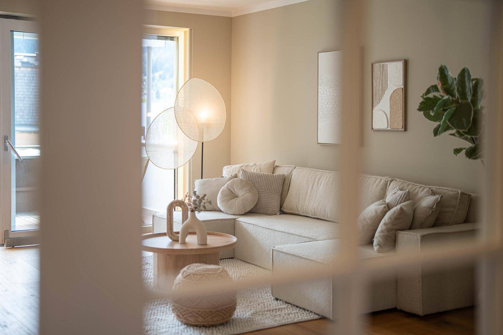 Gemütlicher Wohnbereich mit hellem Sofa, Couchtisch und moderner Stehlampe.