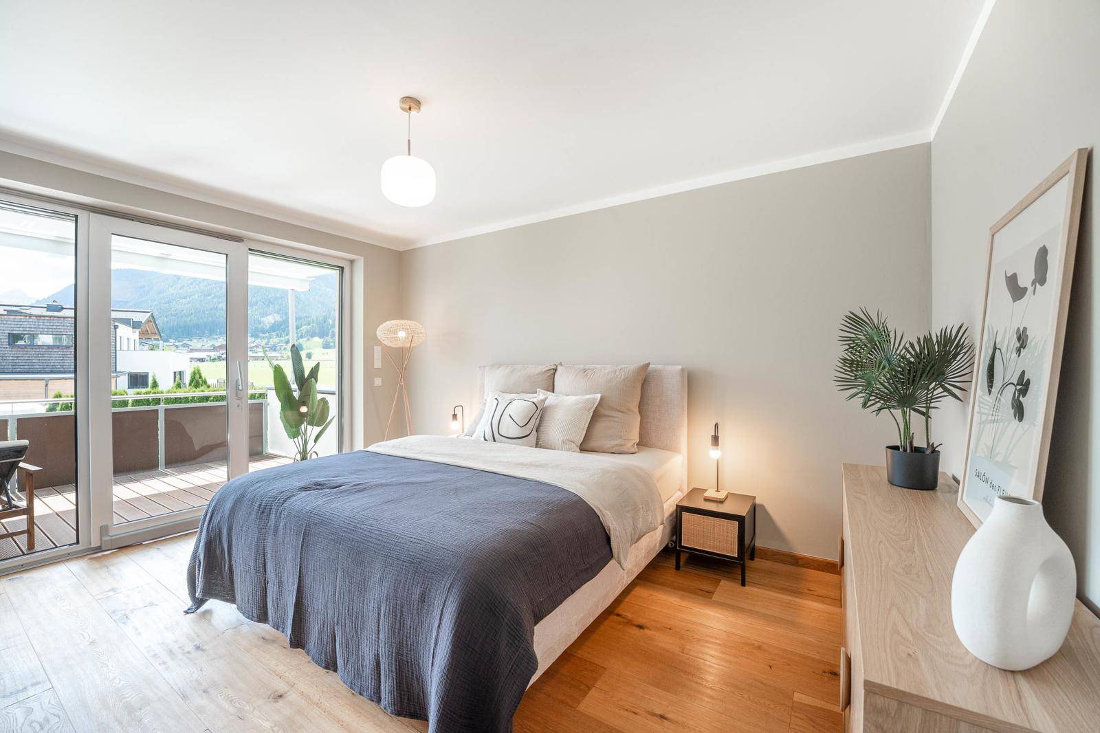 Helles Schlafzimmer mit Holzboden, Doppelbett und Zugang zum Balkon mit Bergblick.