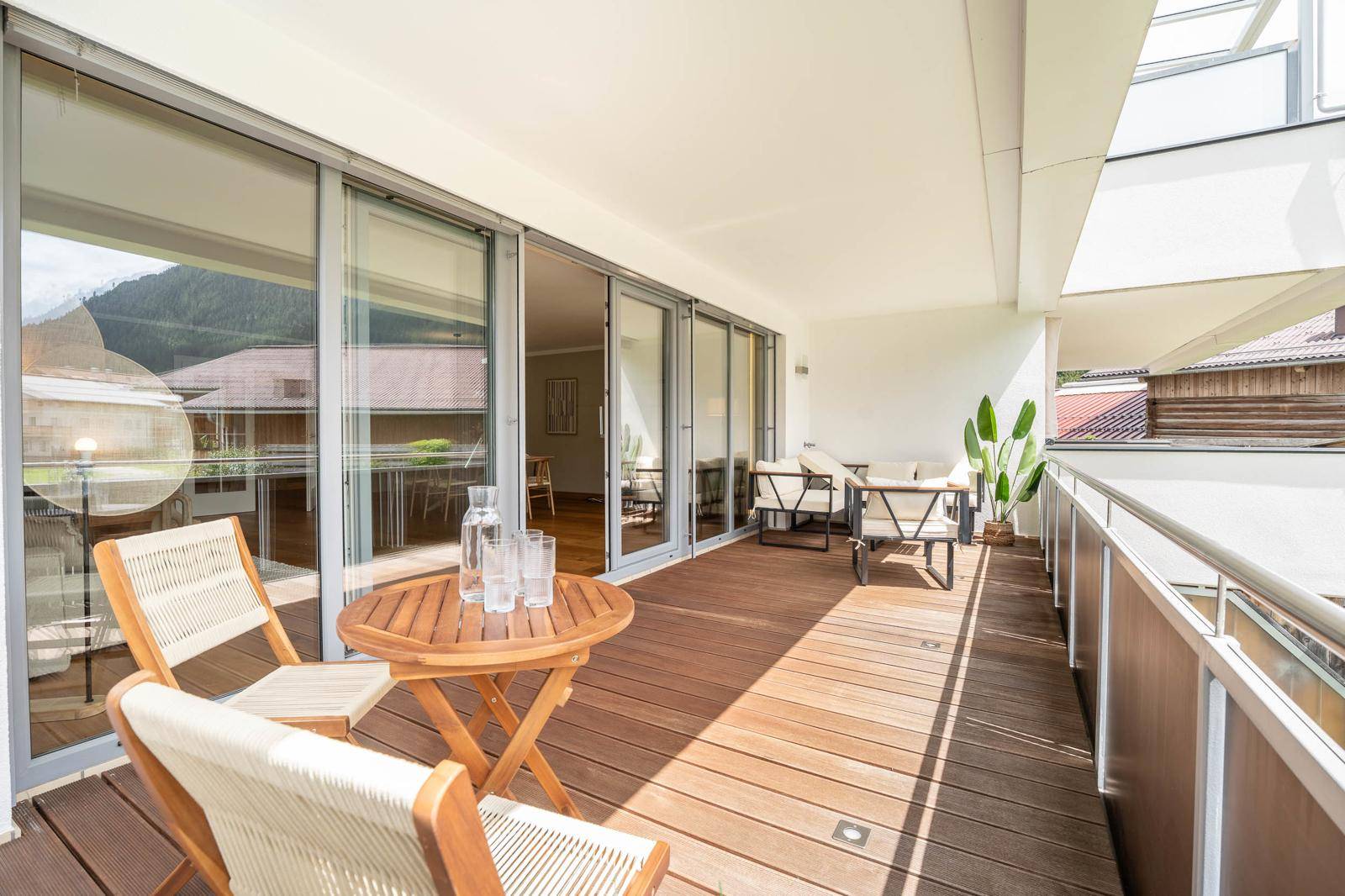 Geräumiger Balkon mit Holzboden, Sitzgelegenheiten und Bergblick.