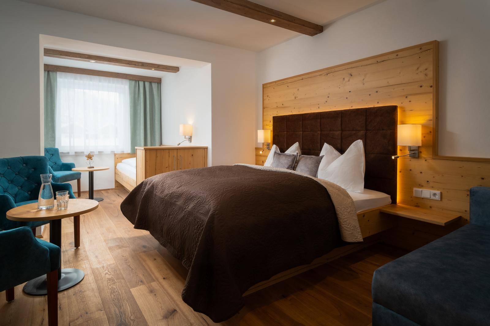 Gemütliches Schlafzimmer mit Holzboden, großem Bett und bequemen Sitzgelegenheiten.