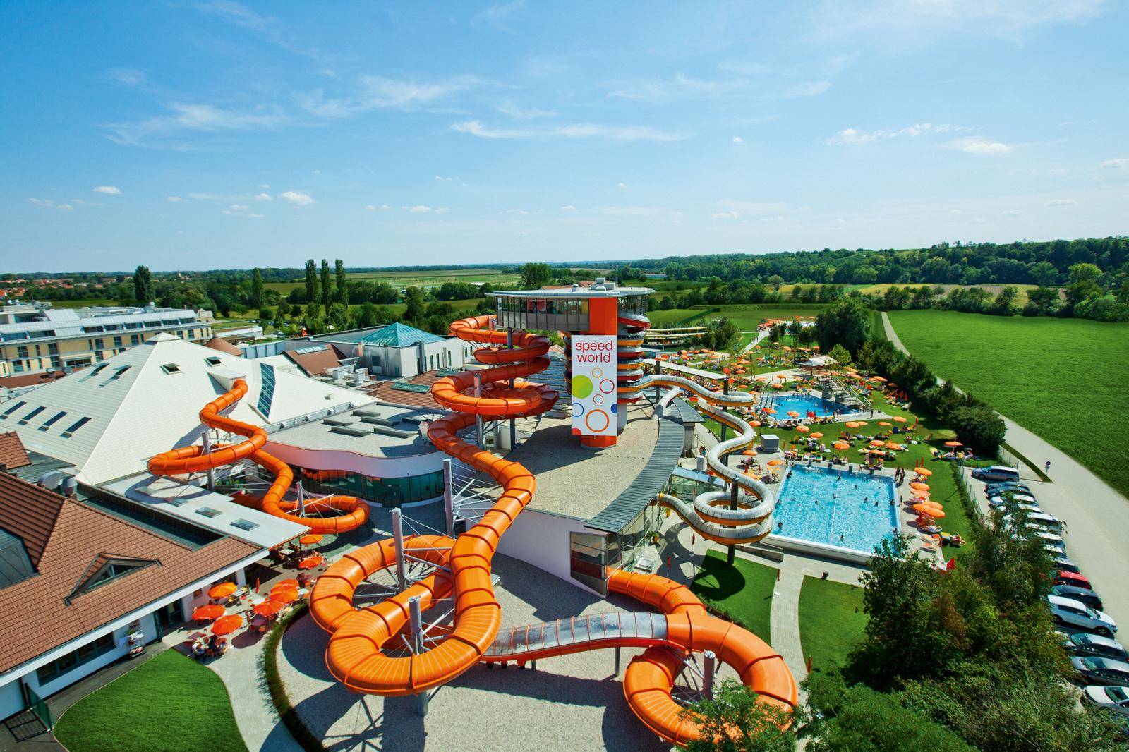 Großzügiger Wasserpark mit zahlreichen Rutschen und Schwimmbecken unter blauem Himmel.
