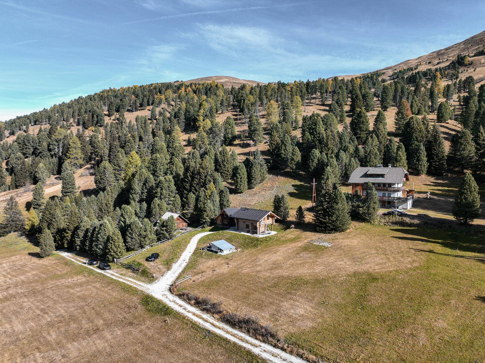 Luftaufnahme einer Ansammlung von Holzhäusern inmitten einer bewaldeten Berglandschaft.