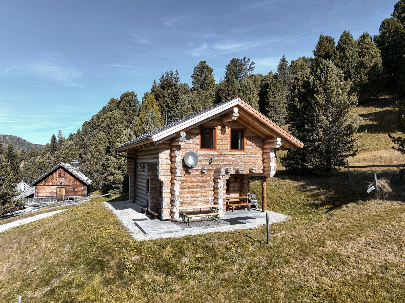 Charmantes Holzblockhaus mit traditioneller Bauweise und Satteldach in sonniger Hanglage.