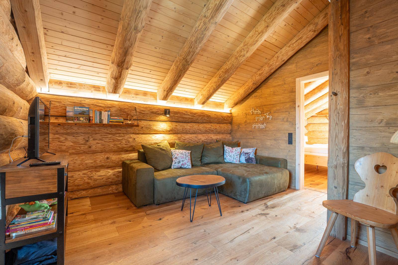 Gemütlicher Wohnbereich im Dachgeschoss mit Holzbalken, Sofa und Holzboden.