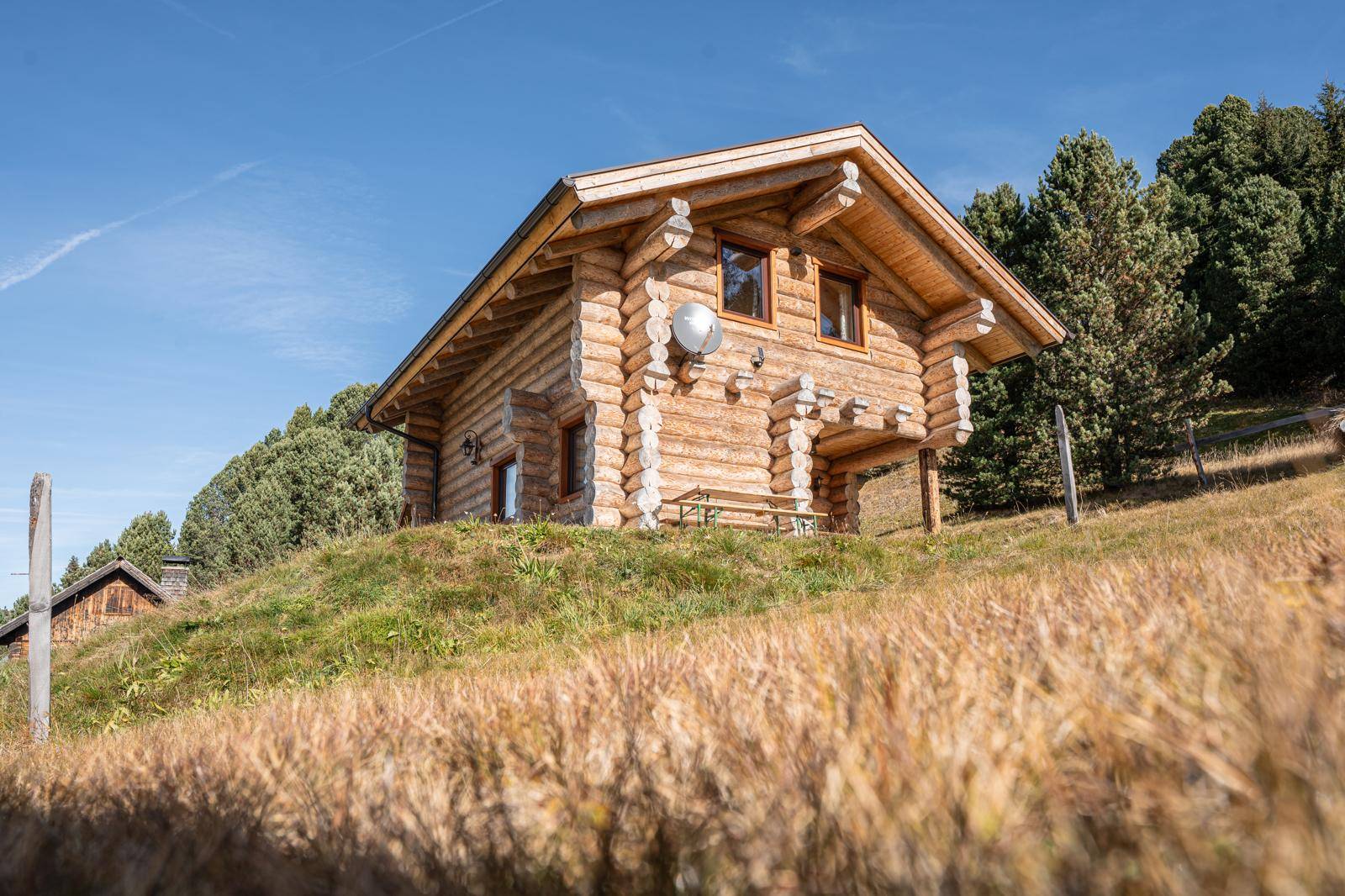 Charmantes Holzblockhaus mit traditioneller Bauweise und Satteldach in sonniger Hanglage.