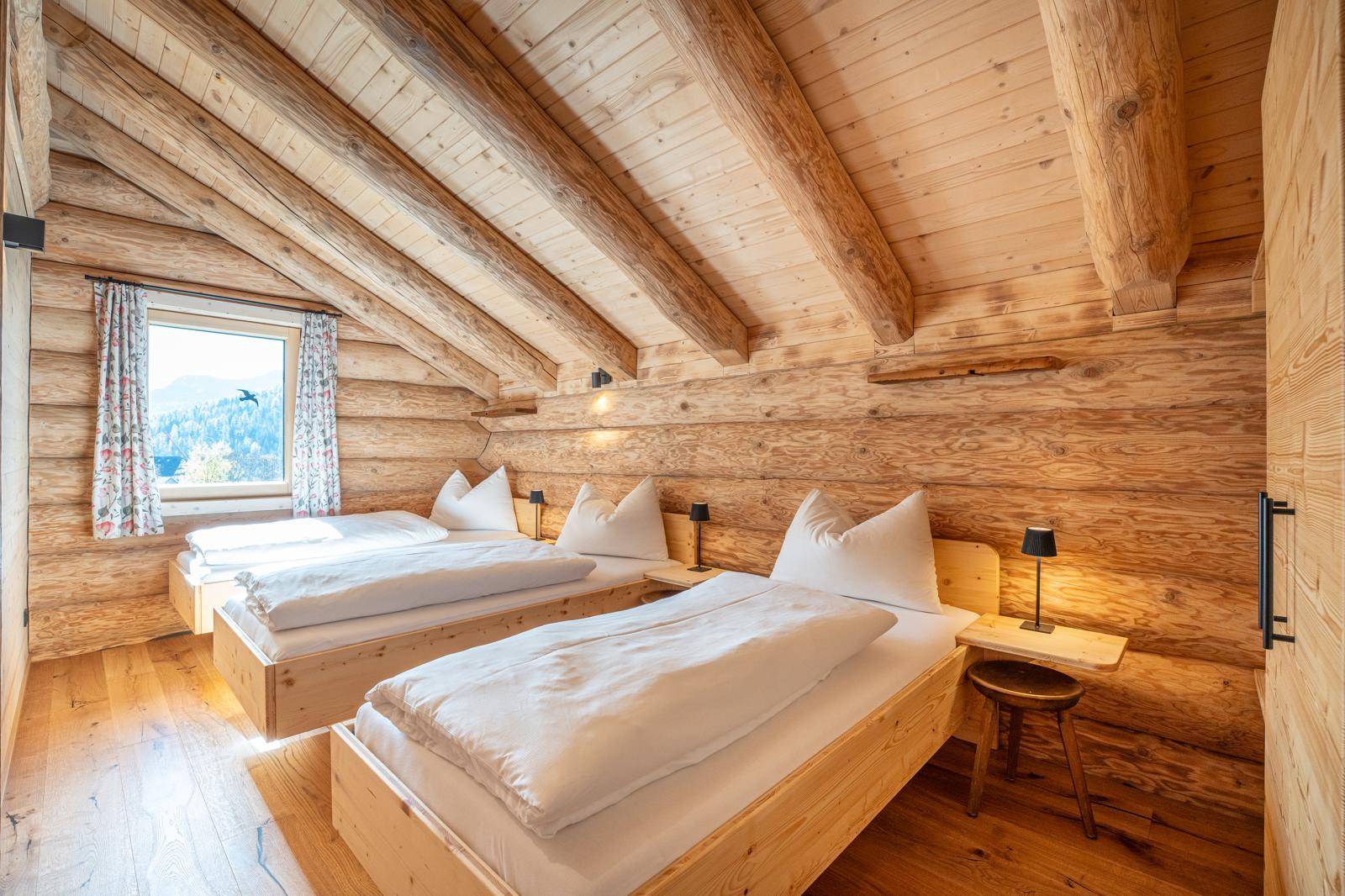 Geräumiges Schlafzimmer mit zwei Einzelbetten, Holzwänden und schrägen Decken.