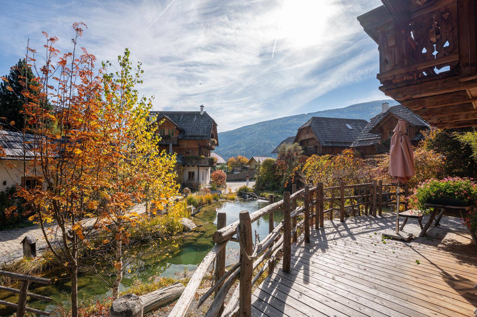 Holzterrasse mit rustikalem Geländer, Blick auf den Teich und die umliegende Landschaft.