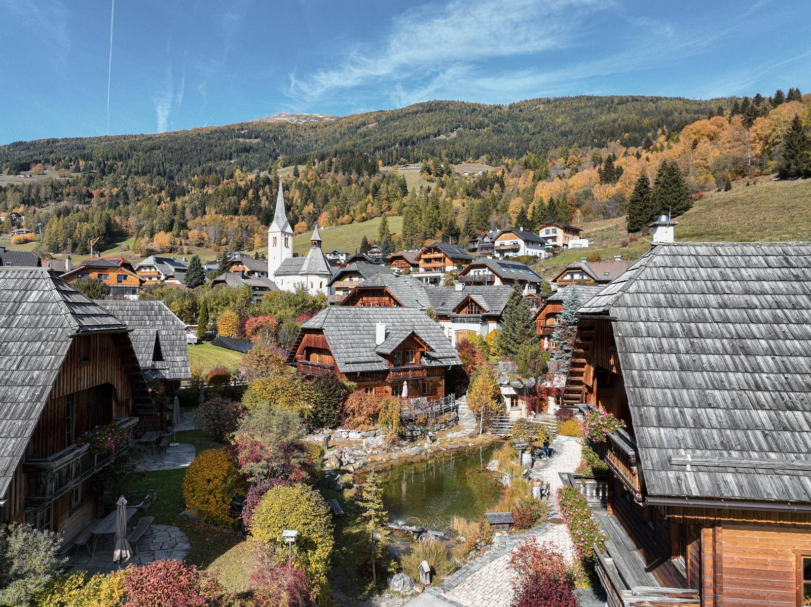 Panoramablick auf ein idyllisches Alpendorf mit traditionellen Holzhäusern und Kirche.