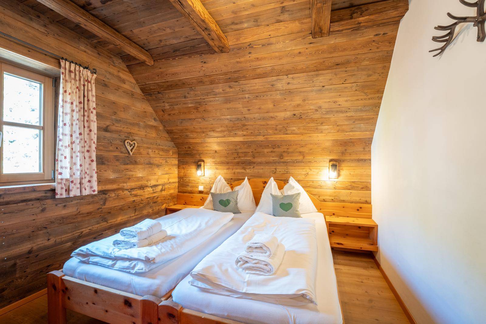 Gemütliches Schlafzimmer mit Holztäfelung, Dachschräge und zwei Betten.