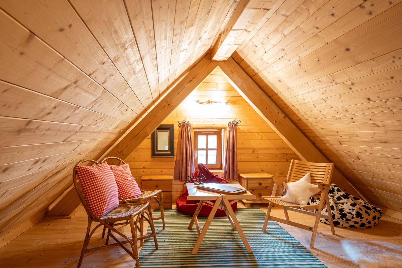 Heller Spitzboden mit Holzverkleidung, Dachschräge und gemütlicher Sitzecke.