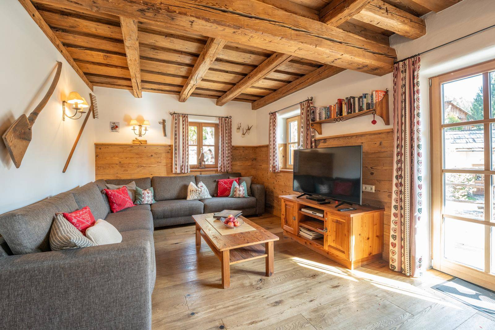 Gemütliches Wohnzimmer im alpinen Stil mit Holzbalkendecke, Holzboden und bequemer Sitzecke.