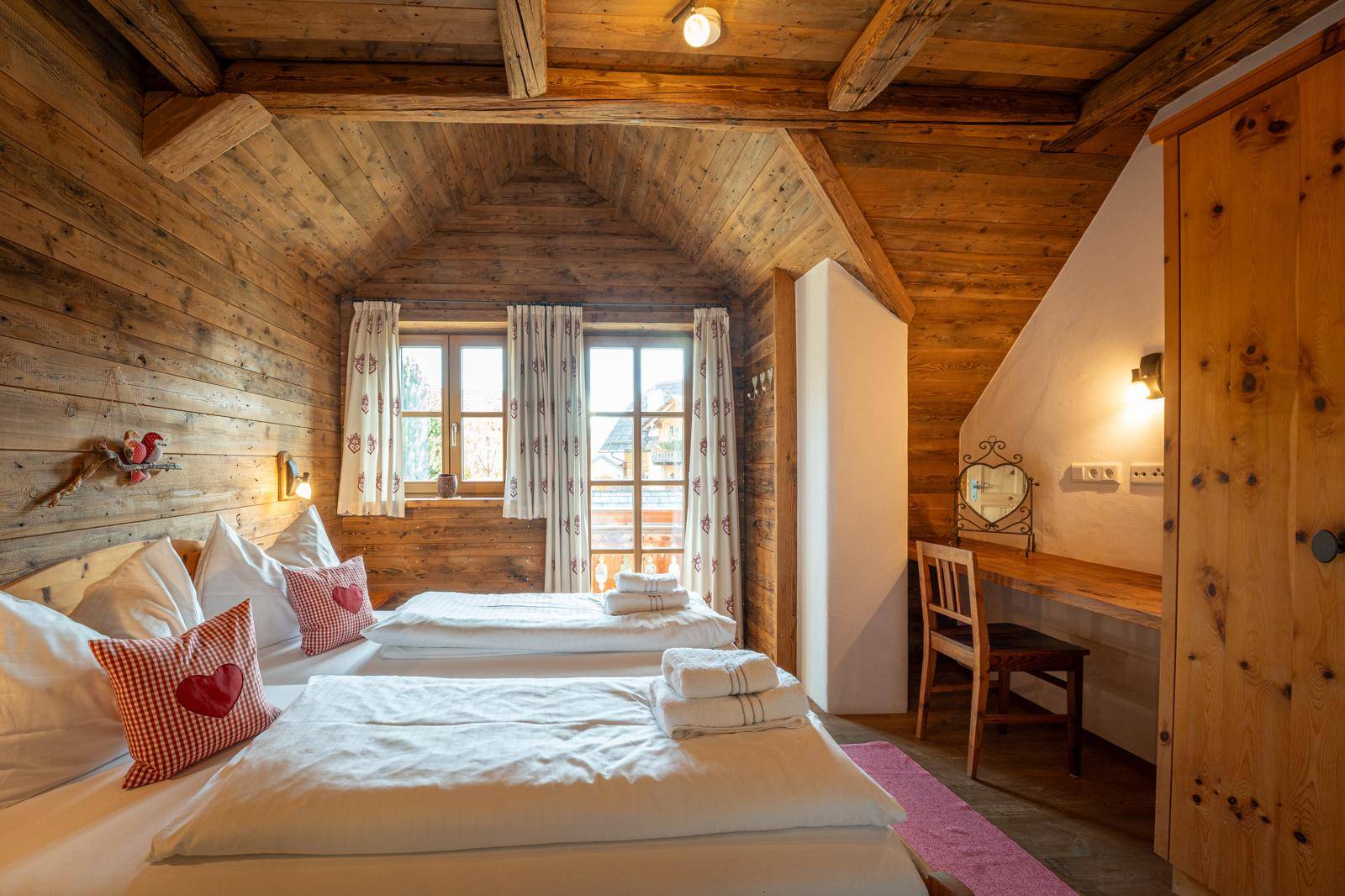 Schlafzimmer im alpinen Stil mit Holztäfelung, Dachschräge und zwei Einzelbetten.