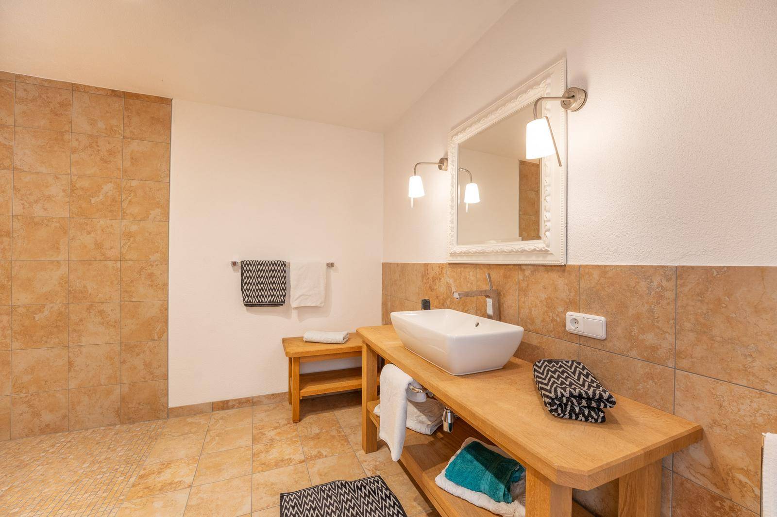Helles Badezimmer mit großformatigen Fliesen, Holzwaschtisch und modernem Aufsatzwaschbecken.