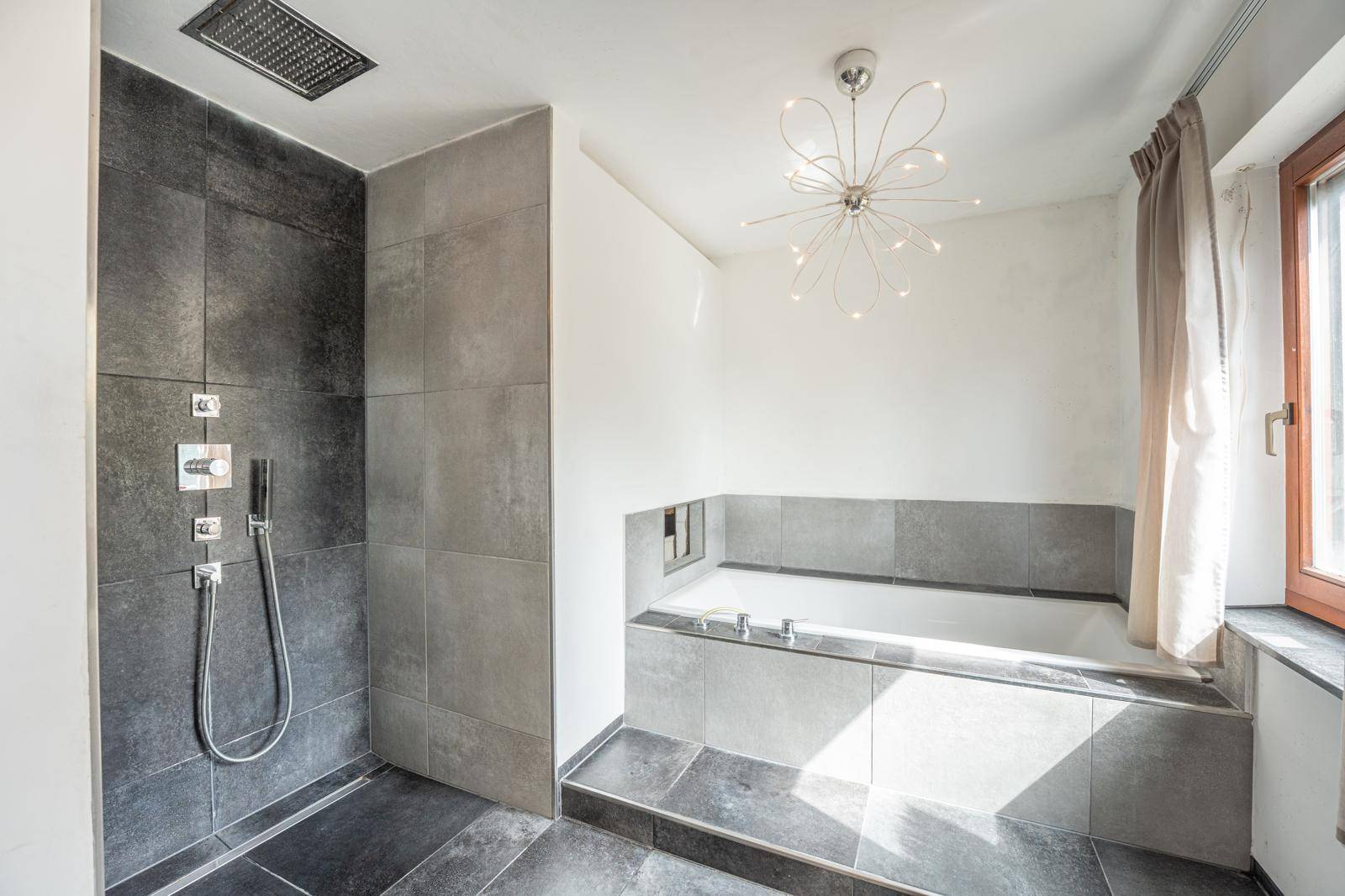 Modernes Badezimmer mit großer Dusche, Badewanne und stilvoller Beleuchtung für entspannende Momente.
