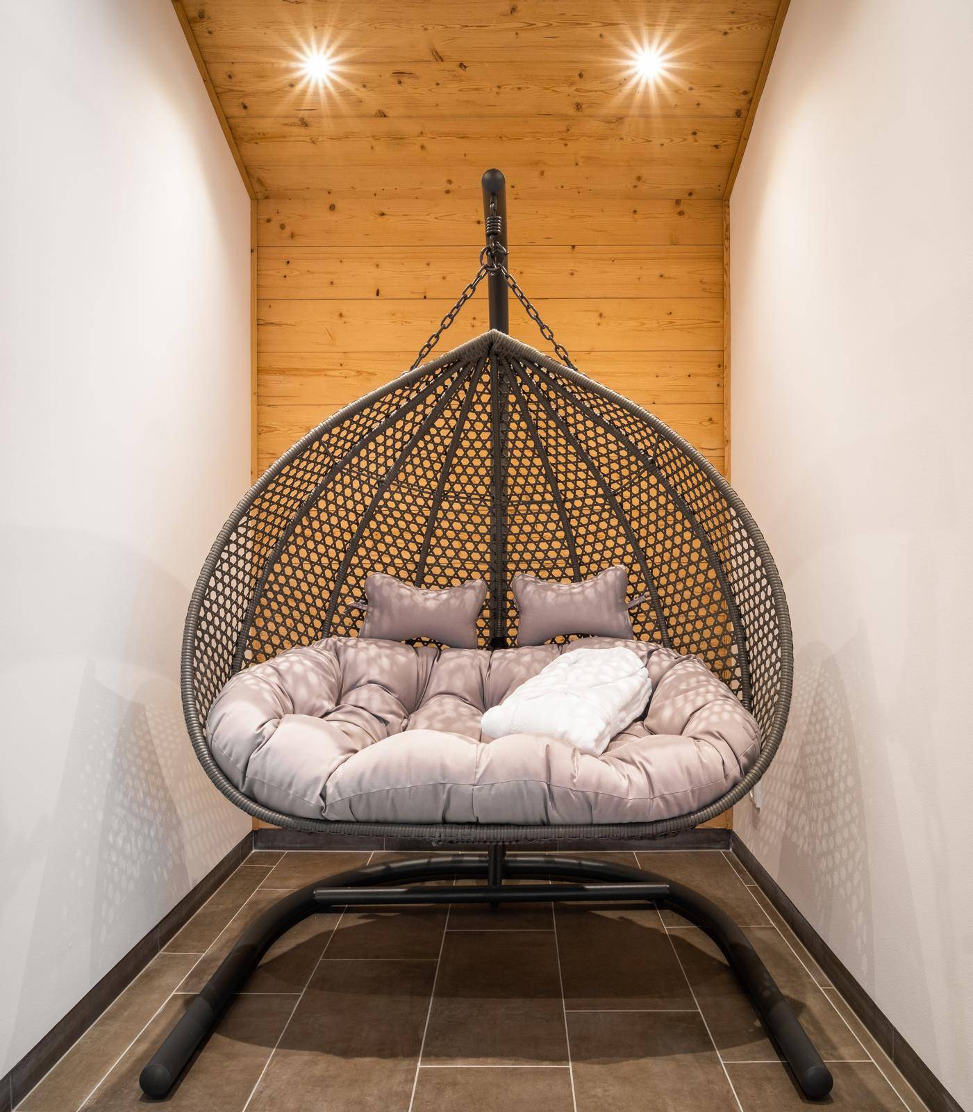 Gemütlicher Entspannungsbereich mit Hängesessel und Holzvertäfelung.