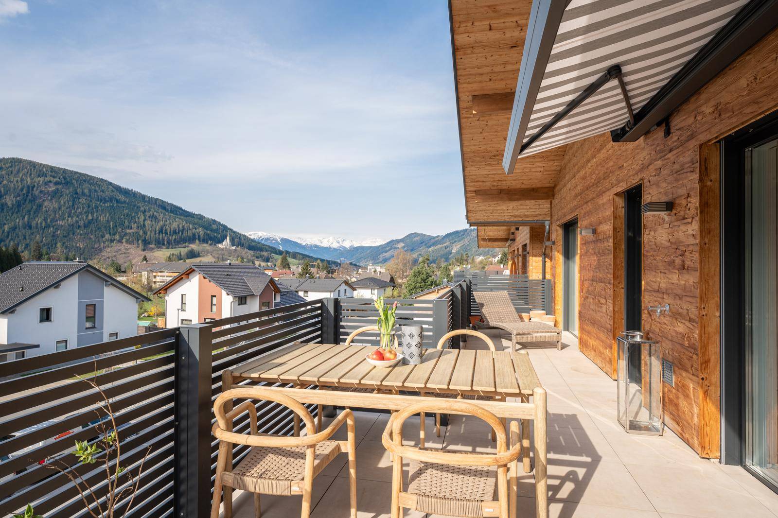 Große Terrasse mit Essbereich, Liegestühlen und atemberaubendem Bergblick.