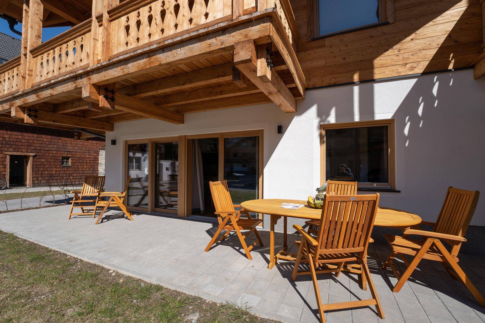 Sonniger Terrassenbereich mit Holztisch und Stühlen, ideal für Mahlzeiten im Freien.
