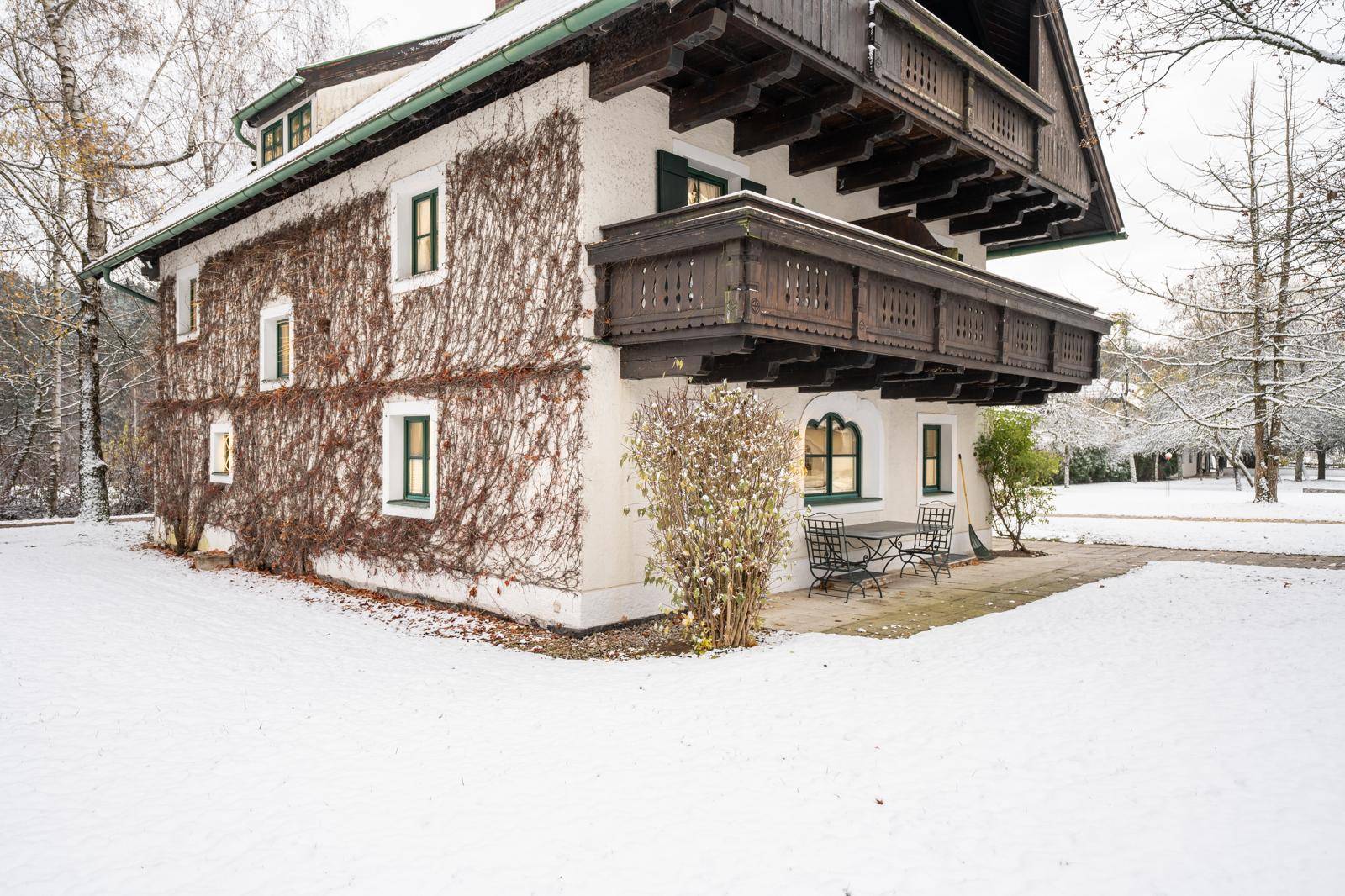 Traditionelles Gebäude im Schnee mit Holzbalkonen und bewachsenen Fassaden.