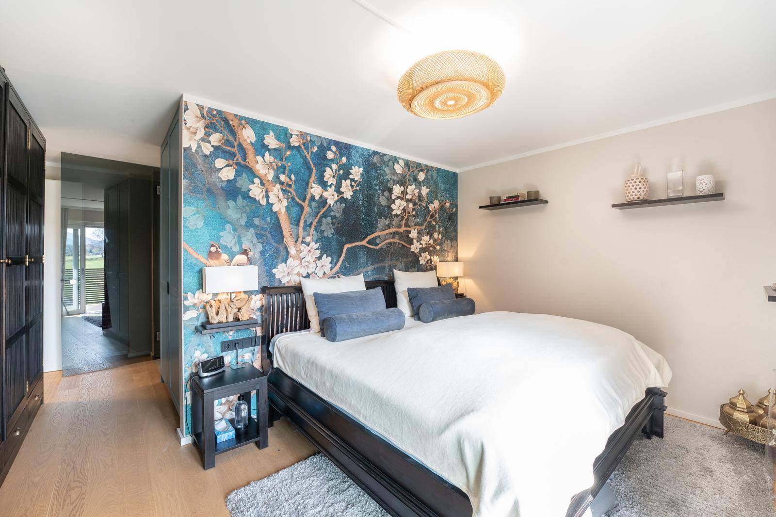 Gemütliches Schlafzimmer mit floraler Tapete, Doppelbett und Holzboden.