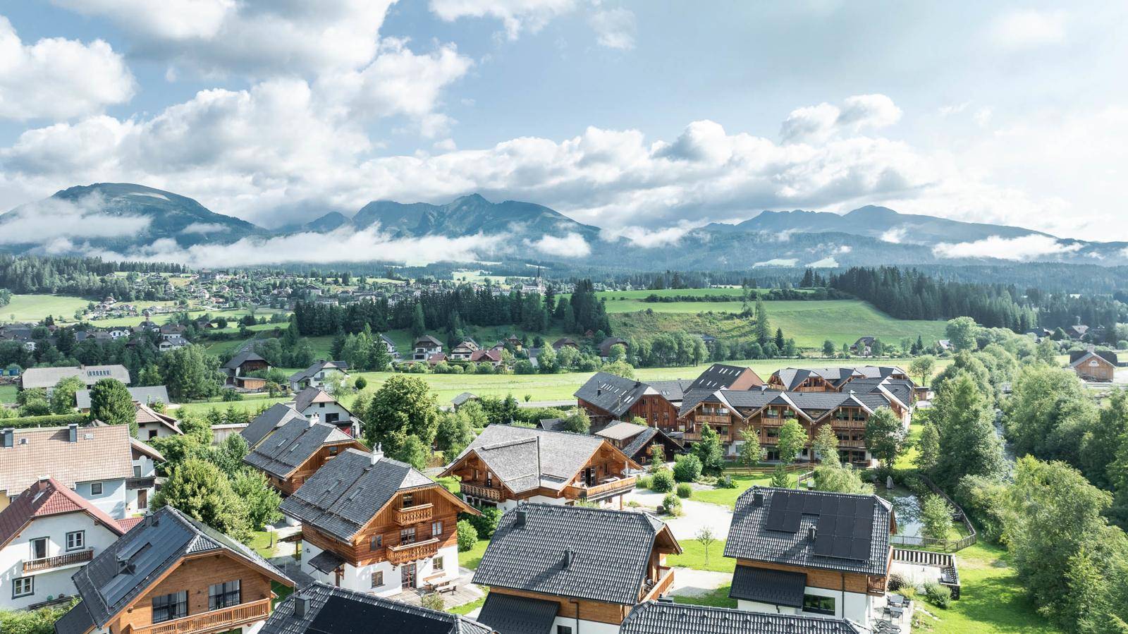 Malerisches Dorf mit traditionellen Chalets, umgeben von grünen Wiesen und Bergen.
