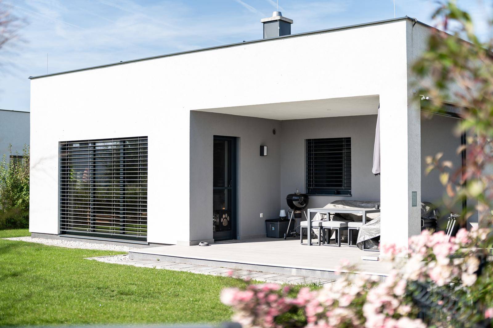 Überdachte Terrasse mit Grillbereich und Gartenmöbeln, ideal für Mahlzeiten im Freien.