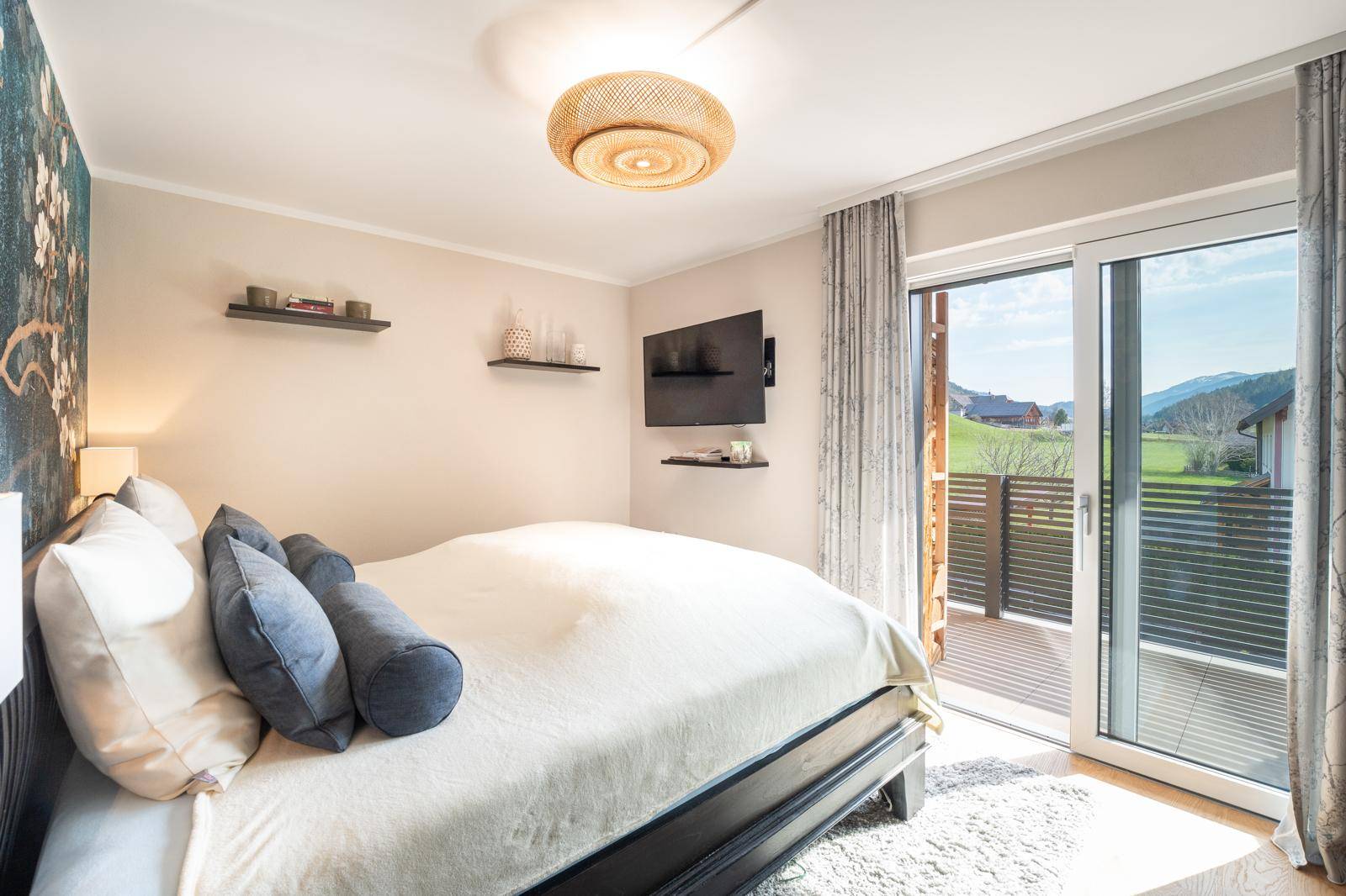 Helles Schlafzimmer mit Balkonzugang, Doppelbett und weitem Blick auf die Landschaft.