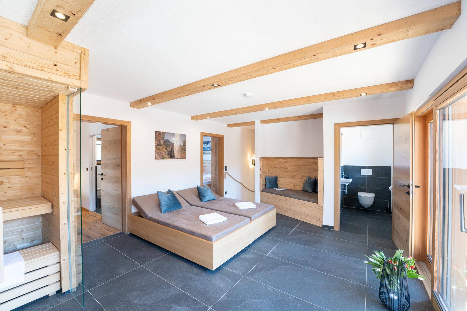Entspannender Wellnessbereich mit Sauna, Liegen und Blick auf ein separates WC.