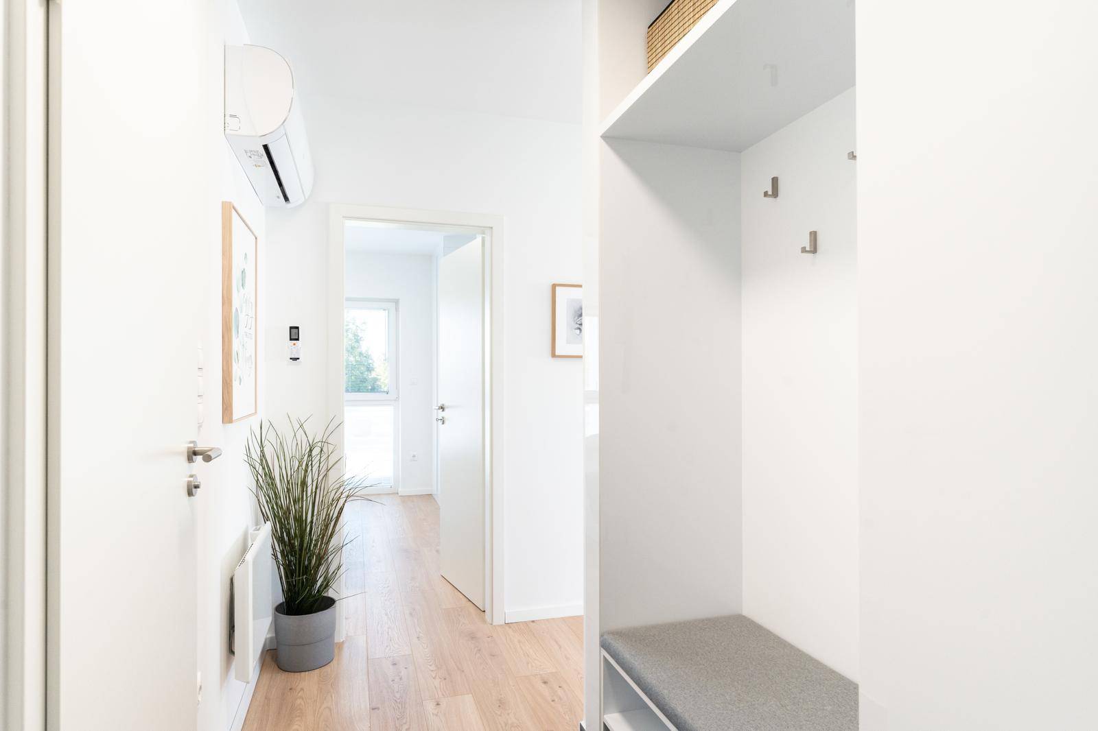 Heller Flur mit Holzboden, integrierter Garderobe und Klimaanlage.