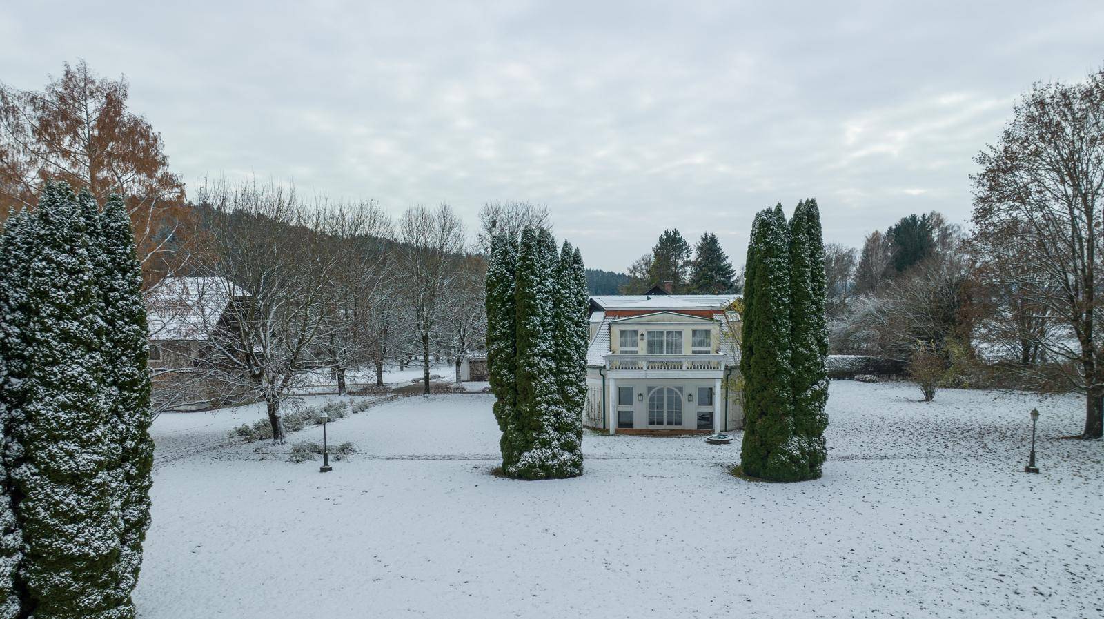 Winterliche Ansicht des Anwesens mit verschneitem Garten und eleganter Villa.