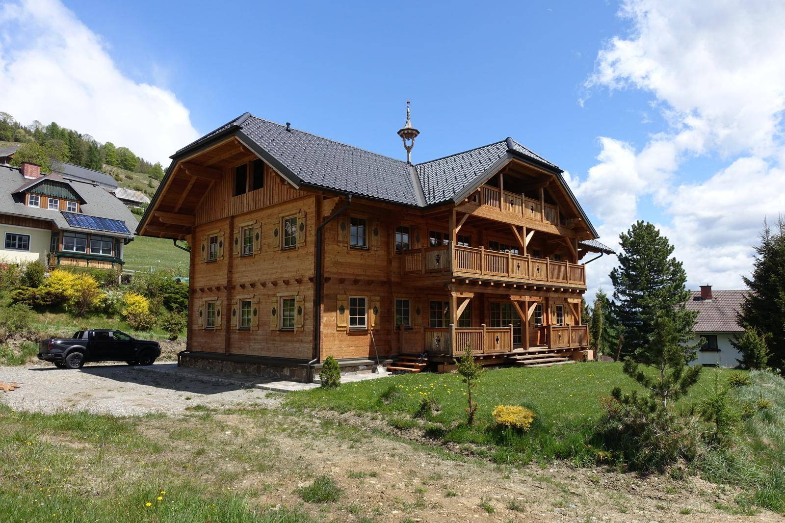 Freistehendes Holzhaus mit Balkonen und Blick auf die umliegende Berglandschaft.