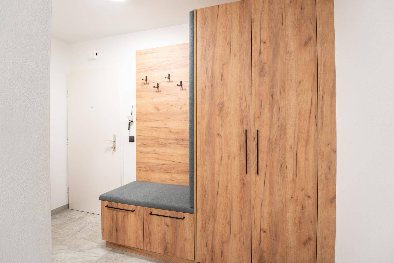 Geräumiger Eingangsbereich mit Holzgarderobe, Sitzbank und Stauraum.