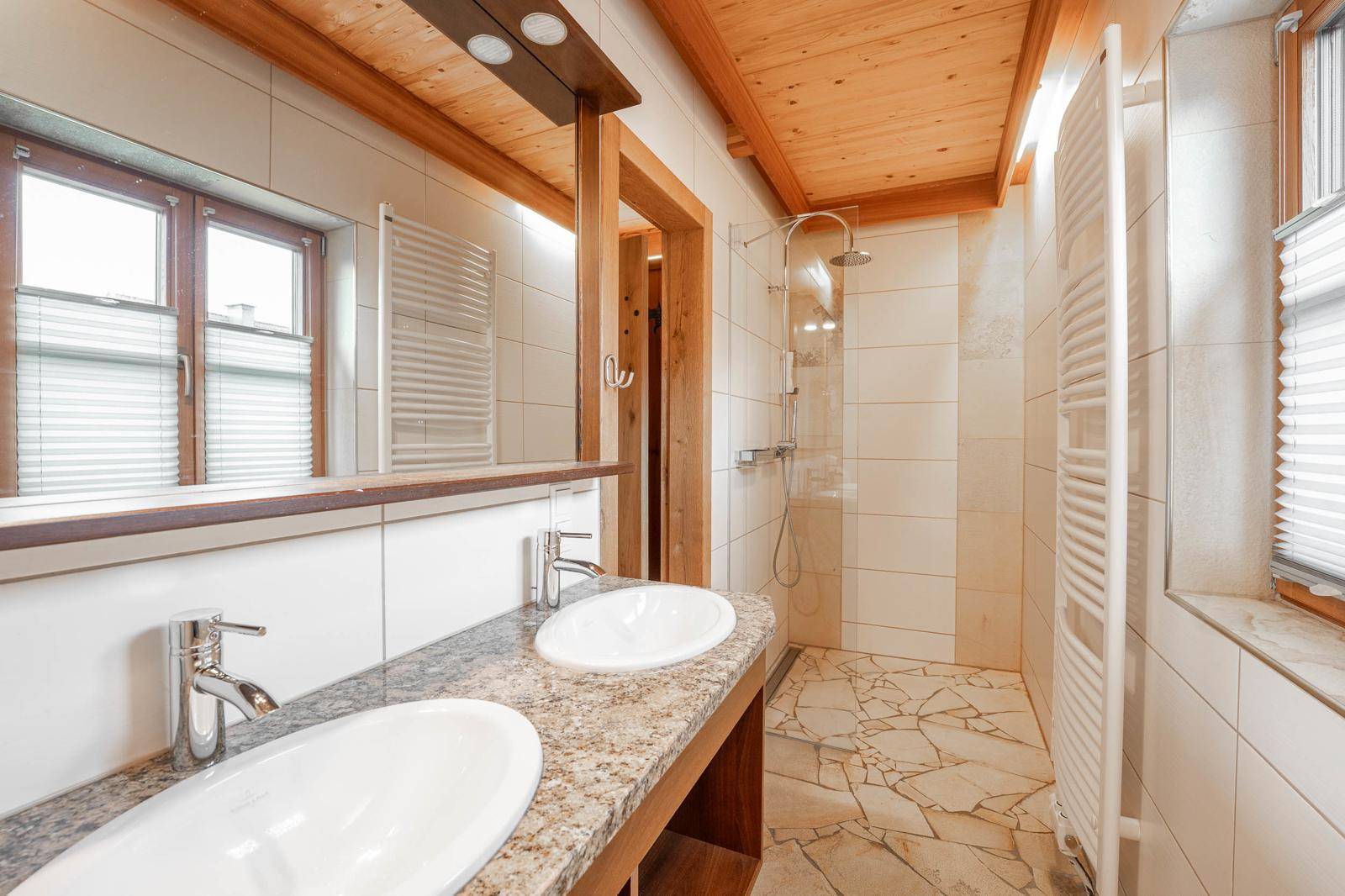 Geräumiges Badezimmer mit Doppelwaschbecken, großer Dusche und Fenster für Tageslicht.