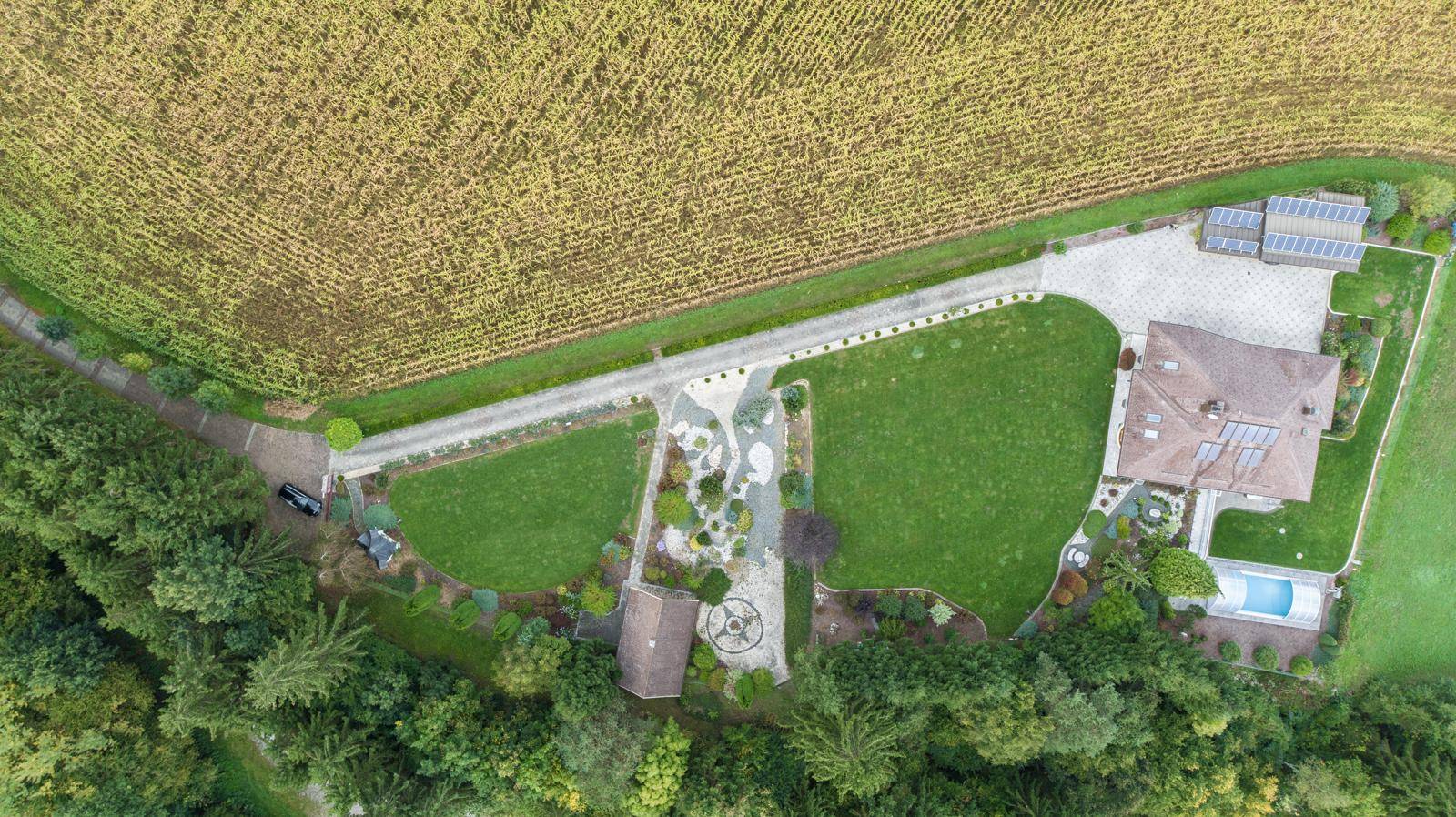 Vogelperspektive des gesamten Anwesens mit Haus, weitläufigem Garten und angrenzenden Feldern.