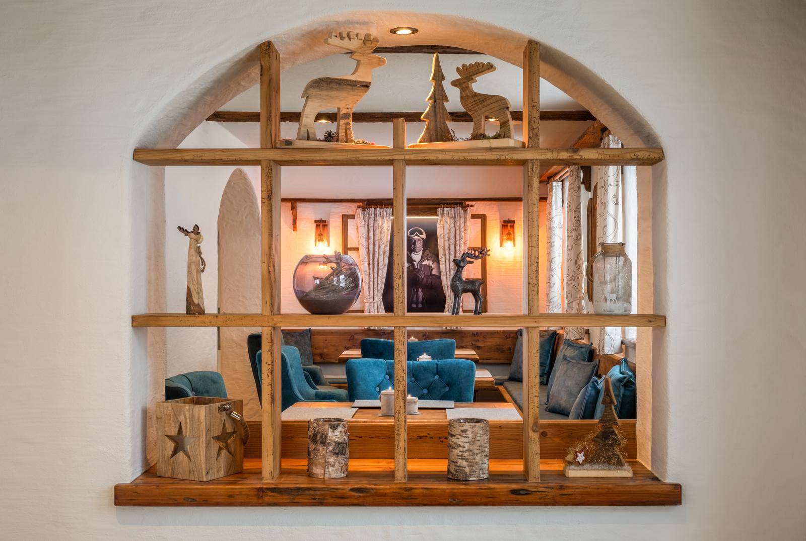 Dekoratives Holzfenster mit alpinen Schnitzereien und Blick in einen gemütlichen Essbereich.