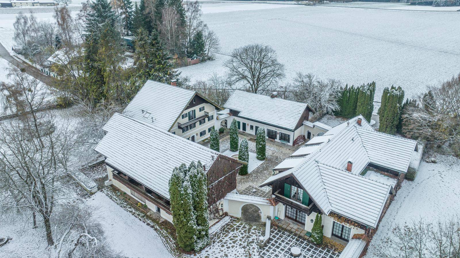 Luftaufnahme des verschneiten Anwesens mit mehreren Gebäuden und weitläufigen Feldern.