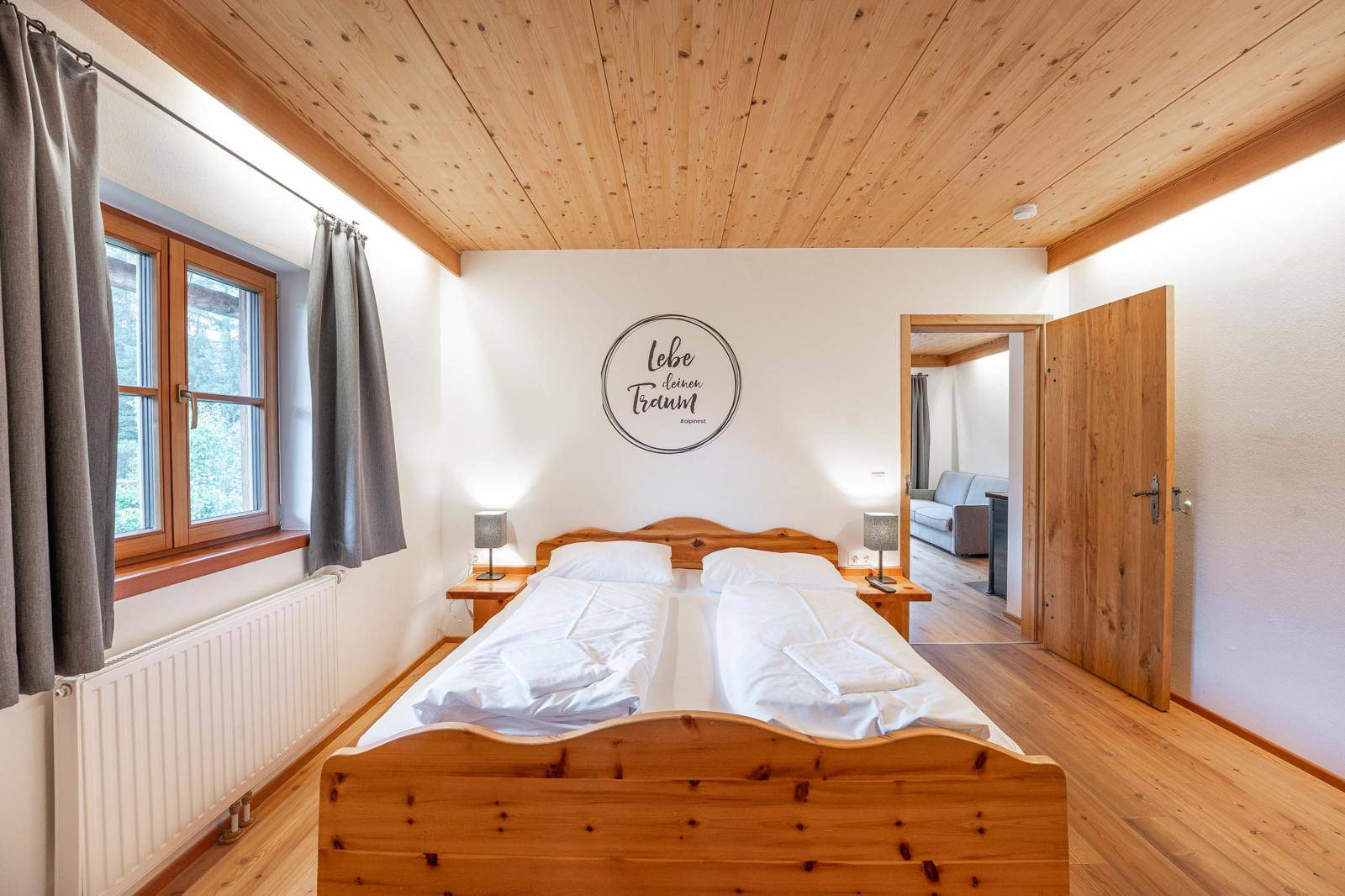 Helles Schlafzimmer mit Holzbett, Holzboden und gemütlicher Atmosphäre.
