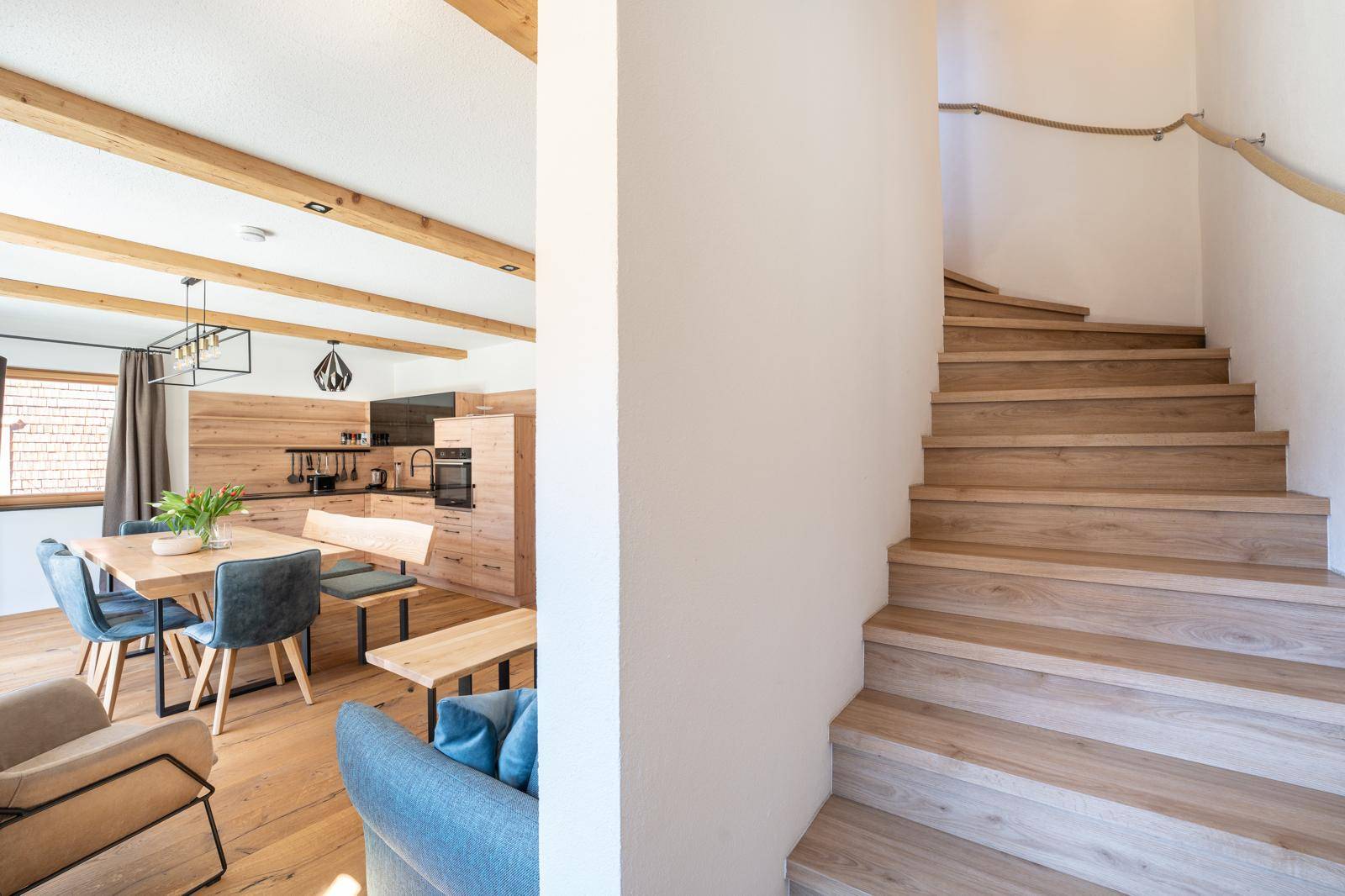 Heller Flur mit Holztreppe, die zum oberen Stockwerk führt, und Blick auf den Wohnbereich.