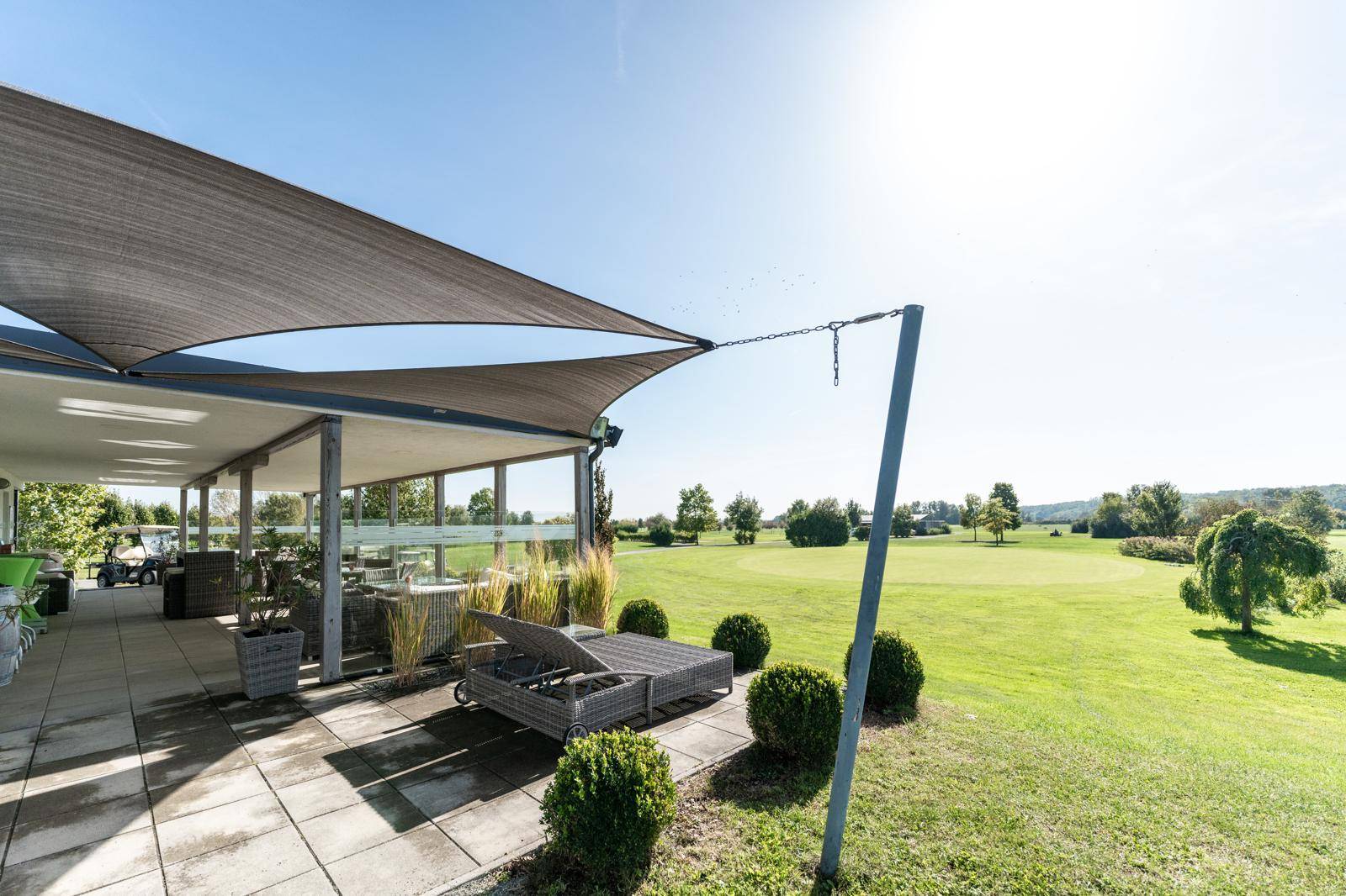 Großzügige Terrasse mit Sonnenschutz und Liegemöglichkeiten, direkt am Golfplatz gelegen.