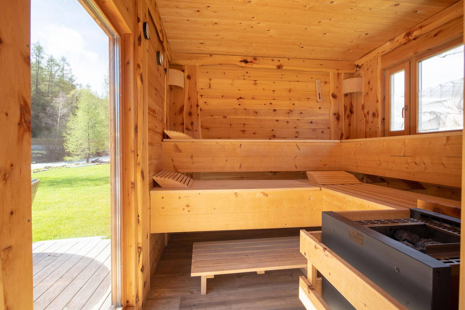 Traditionelle Holzsauna mit mehreren Bänken und Blick ins Grüne.