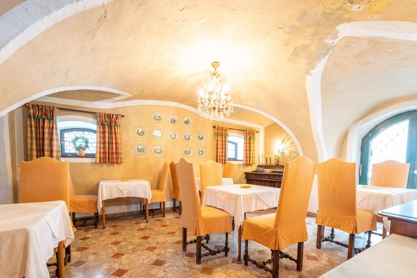 Eleganter Speisesaal mit Kronleuchter, Gewölbedecke und traditionellen gelben Stühlen.