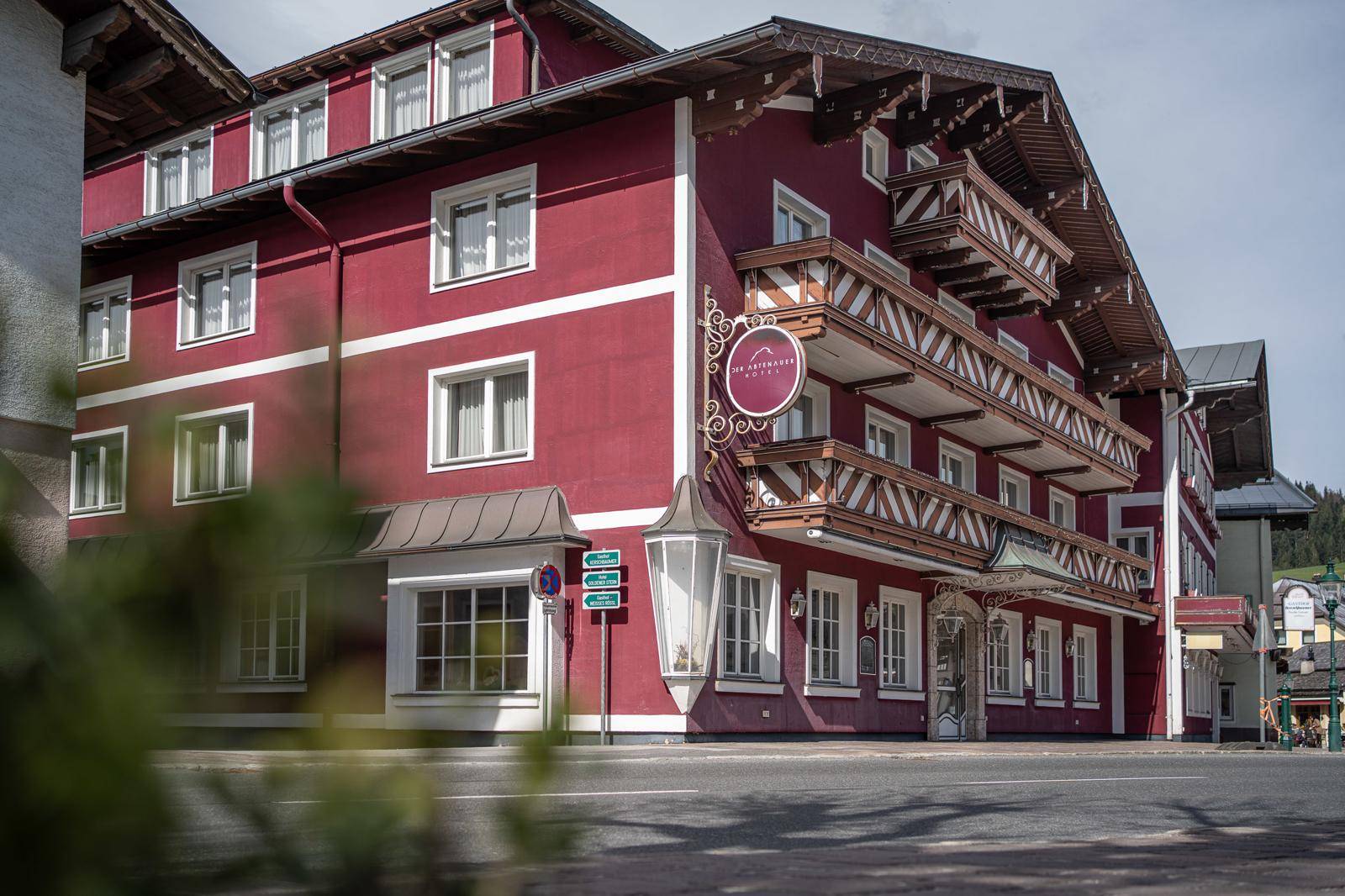 Detailansicht der roten Fassade mit traditionellen Holzbalkonen und dem Eingangsbereich des Gebäudes.