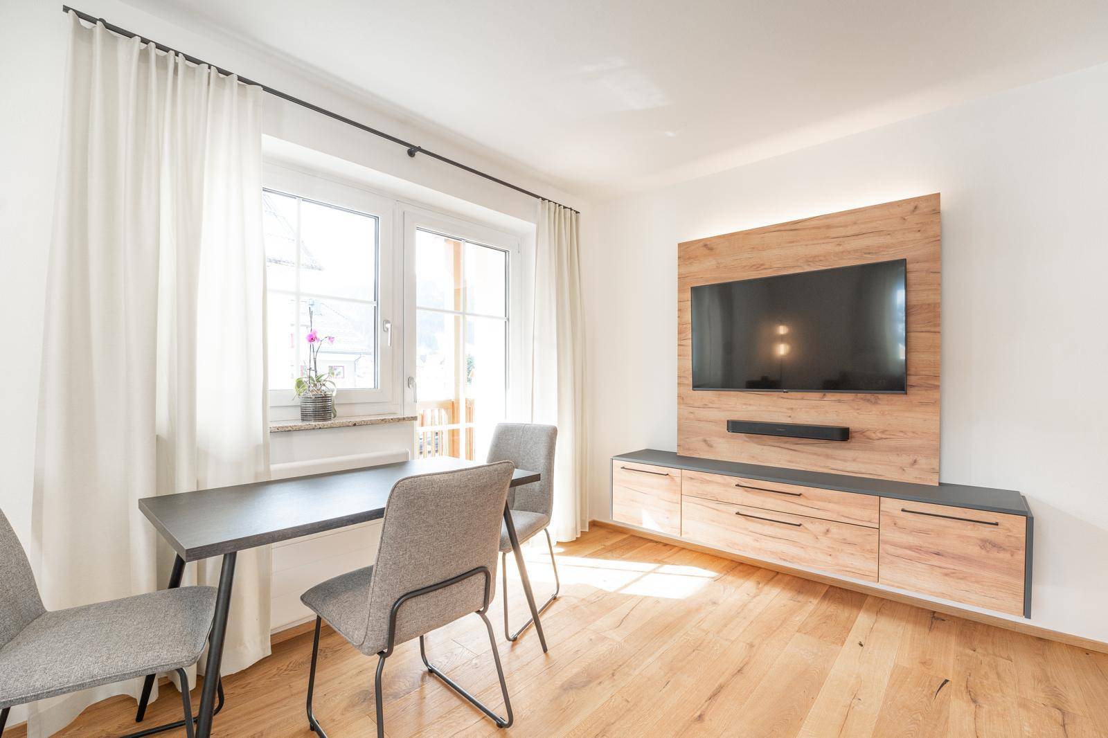 Moderner Essbereich mit Holzboden und einem an der Wand montierten Fernseher.