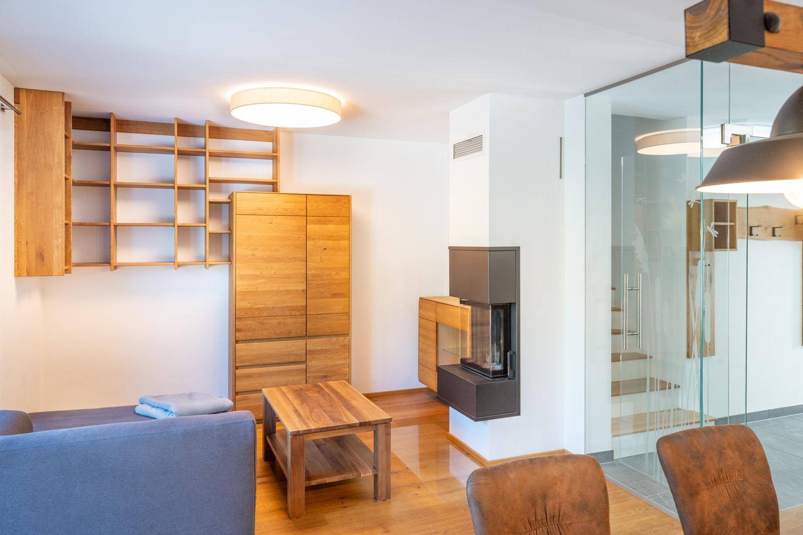Heller Wohnbereich mit modernem Kamin, Holzboden und Glasabtrennung zum Treppenhaus.