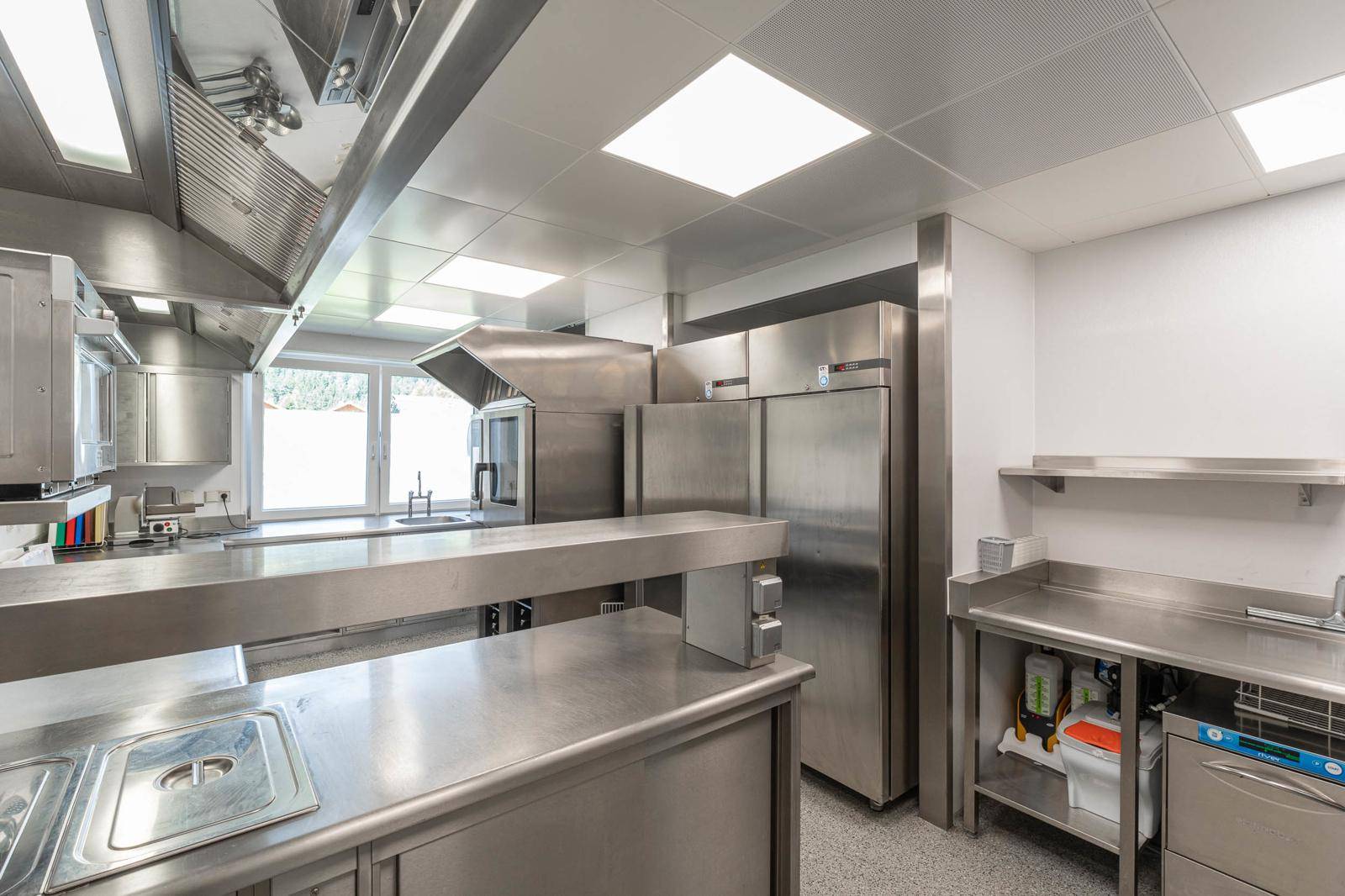 Professionelle Großküche mit Edelstahloberflächen, modernen Geräten und viel Arbeitsfläche.