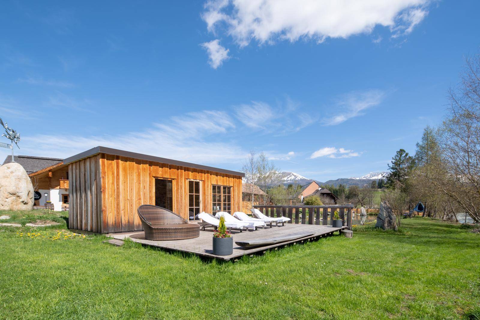 Entspannungsbereich im Garten mit Holzterrasse, Liegestühlen und Bergblick.