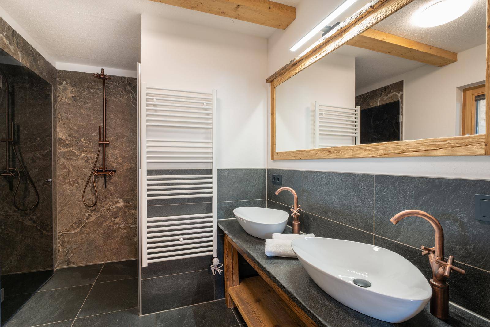Elegantes Badezimmer mit zwei Waschbecken, begehbarer Dusche und beheiztem Handtuchhalter.