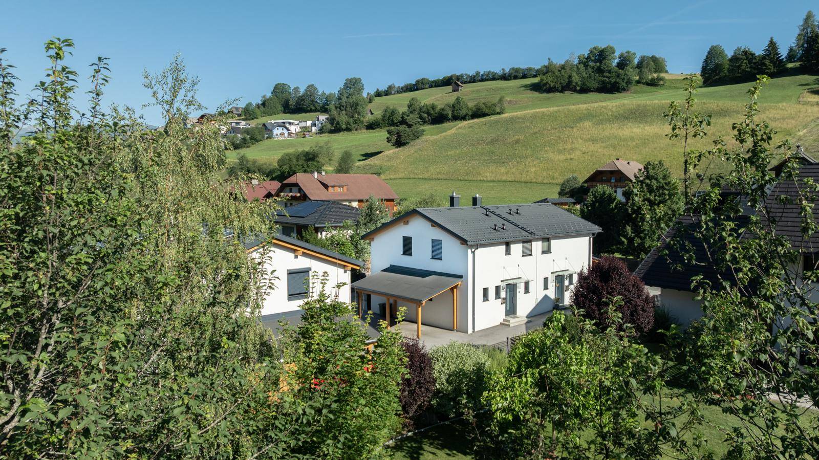 Freistehendes Haus in ländlicher Umgebung mit grünen Hügeln und Bäumen.